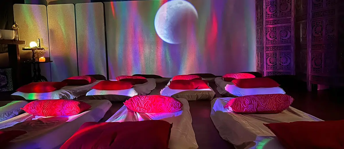Intimate group reiki healing space at The Ascension Loft in Abbotsford — floor mattresses with pillows under coloured atmospheric lighting