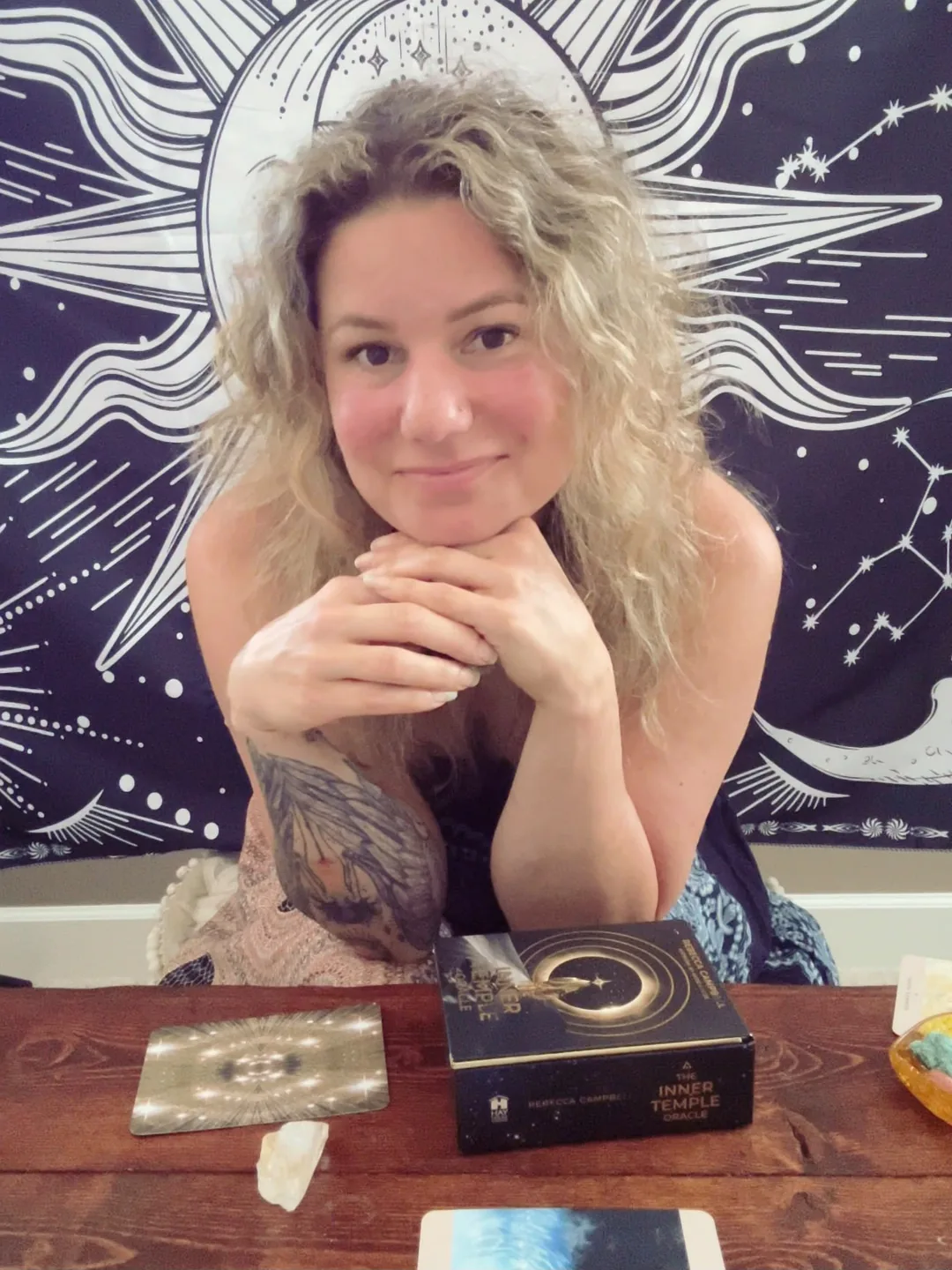Tracy Brown at her reading table with an oracle deck and a drawn card laid out in front of her