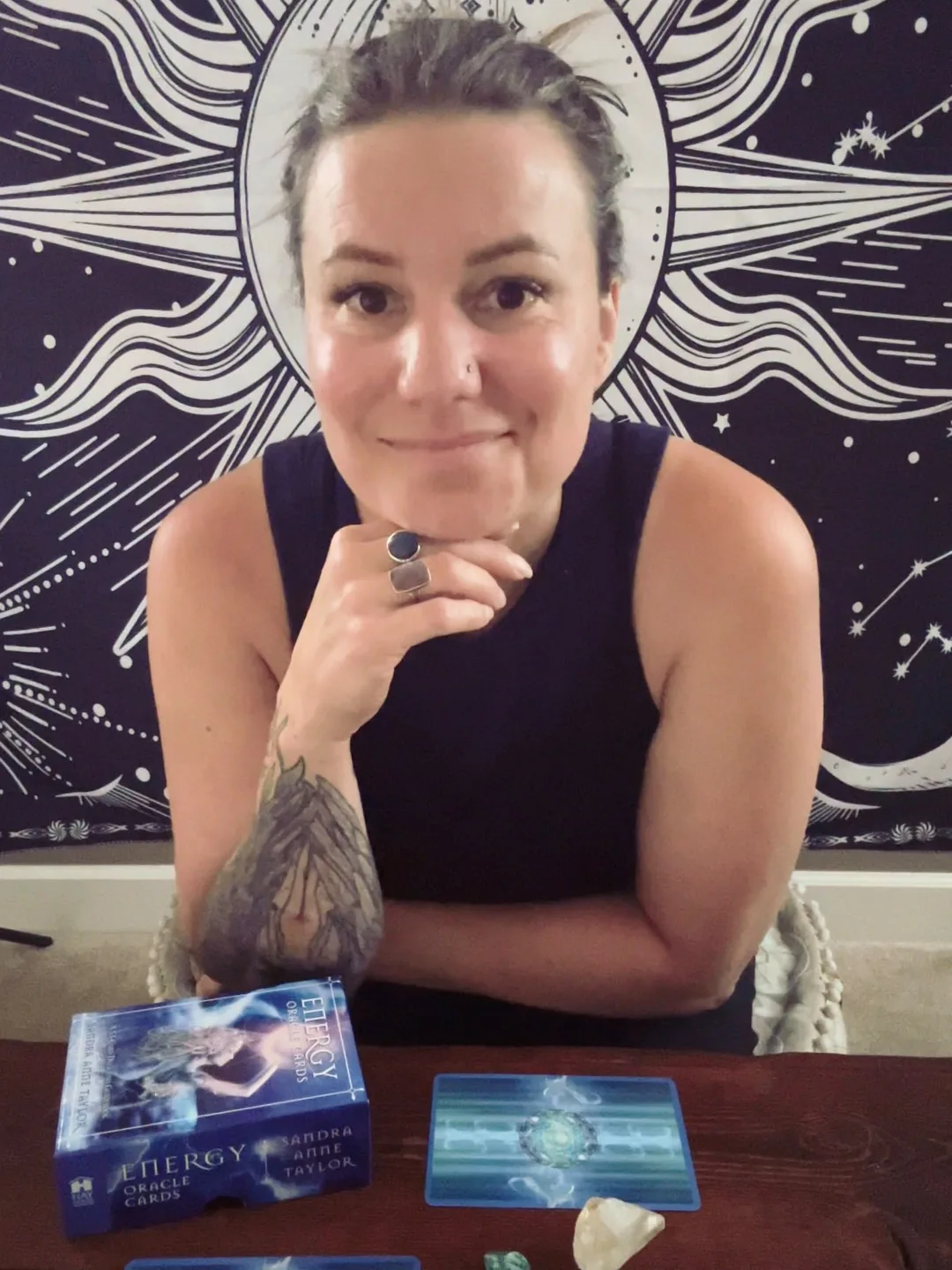 Tracy Brown listening at her reading table, an oracle deck and two cards in front of her