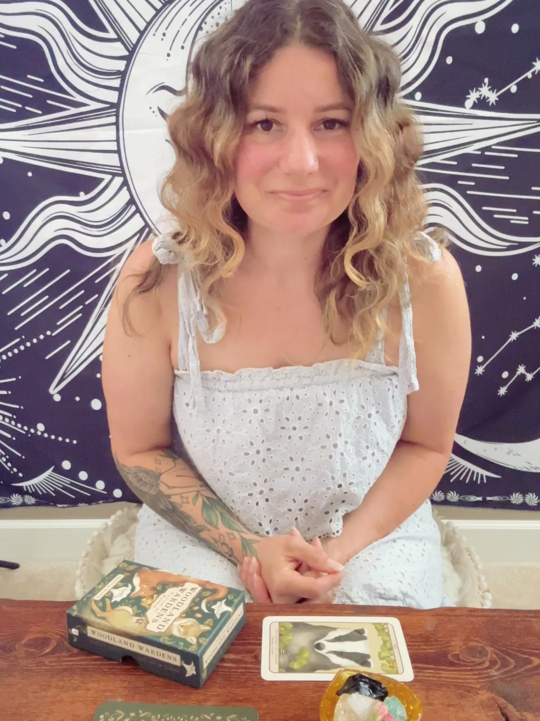 Tracy Brown seated at her reading table with an oracle deck and a card drawn beside her